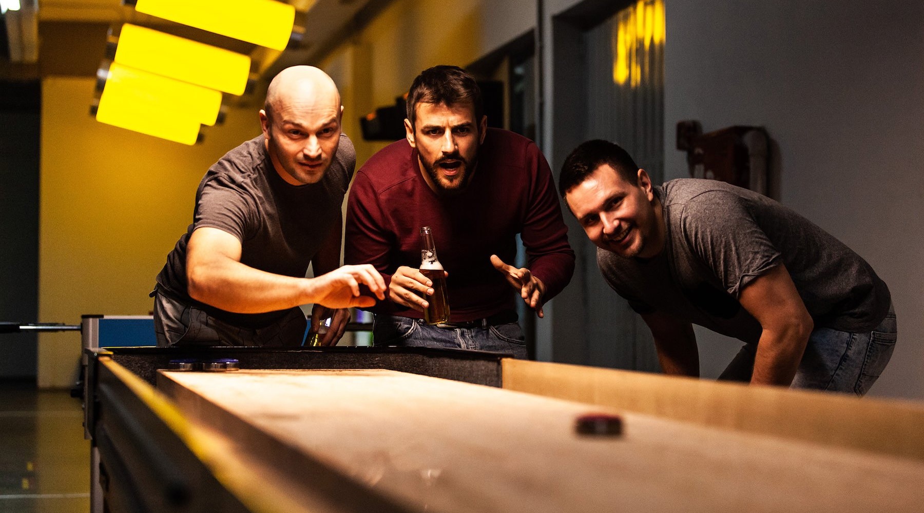 three men playing on a shuffleboard